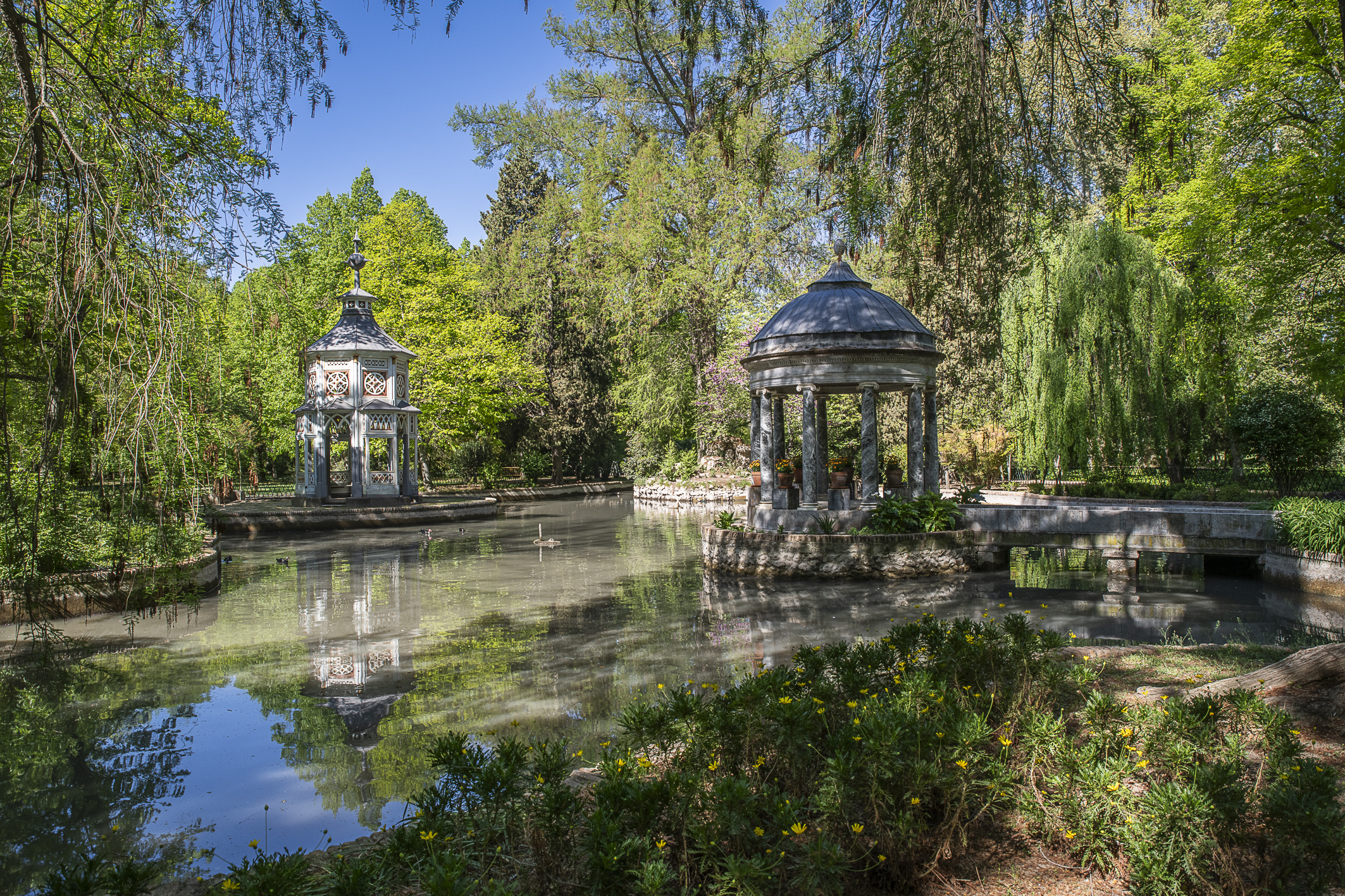 Fotografía actual del estanque chinesco del Jardín del Príncipe con dos templetes reflejados.